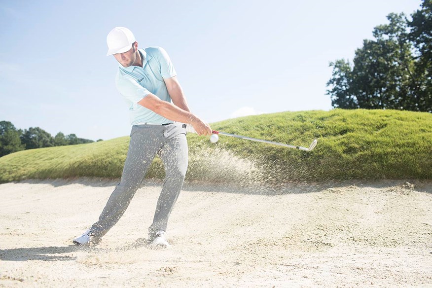 Jon Rahm plays a shot from a bunker.